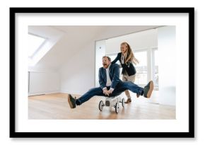 Playful businesswoman pushing businessman on toy car in office