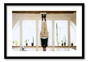 Office clerk having fun, doing headstand without hands on wooden table in modern office at work time. Concept of business, healthy lifestyle, sport, hobby