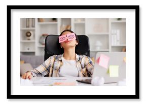 The concept of a lot of work. Tired Indian student girl sleeping with stickers on her eyes while sitting at the table. Distracted woman in home office.