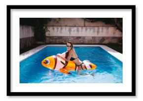 Funny young woman on top of a mattress fish in the pool