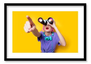 Young style girl in purple clothes with binoculars on yellow background.  Clothes in 1980s style