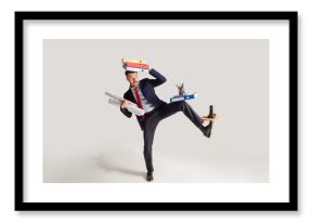 Young businessman in a suit juggling with office supplies in his office, isolated on white background. Conceptual collage with phone, folders. The business, office, work concept.