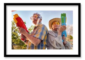 Modern Senior couple have fun playing with  water gun.