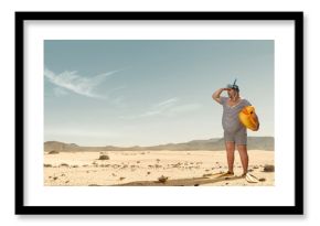 Funny overweight swimmer looking for the beach  in the middle of the desert with copy space