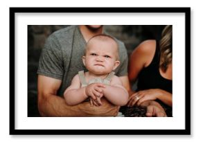 Baby boy making funny face sitting with parents