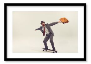 Young funny man, businessman dressed in suit in 50s, 60s fashion style rides skateboard isolated on white background. Retro vintage style, business, ad, emotions