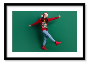 Full length photo of funny carefree lady wear red ugly print xmas sweater cap walking isolated green color background
