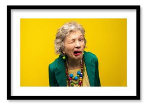 Senior woman making funny faces against yellow background