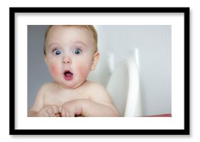 surprised kid sitting at table. child's eyes widened and mouth opened in amazement. copy space for your text