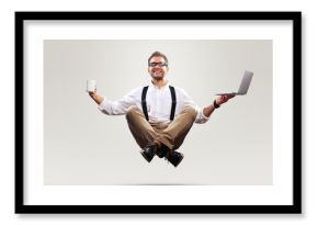 Young man is soaring in the air with a Cup of coffee and a laptop