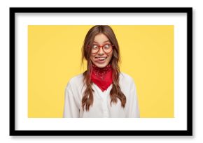 Photo of crazy girlfriend makes funny face, crosses eyes and sticks out tongue, plays fool, doesnt want to be responsible, being in good mood, models indoor against yellow studio background.