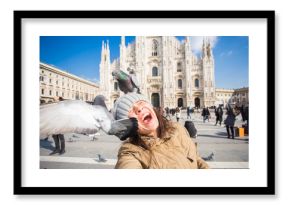 Winter travel, vacations and birds concept - Young happy woman tourist with funny pigeons making selfie photo in front of the famous Duomo cathedral in Milan.