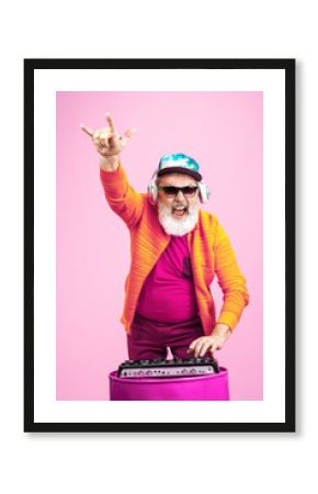 Party drive. Portrait of senior hipster man in fashionable eyewear isolated on pink studio background. Tech and joyful elderly lifestyle concept. Trendy colors, forever youth. Copyspace for your ad.