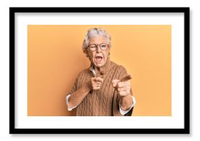Senior grey-haired woman wearing casual clothes and glasses pointing fingers to camera with happy and funny face. good energy and vibes.