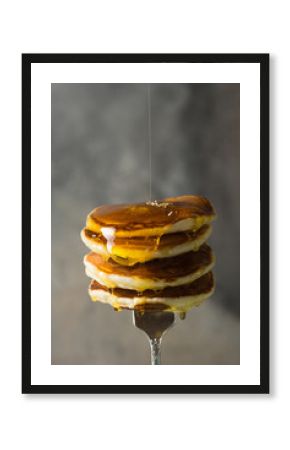 Tasty breakfast. Homemade stack pancakes on fork with  honey or maple syrup on  grey  background.