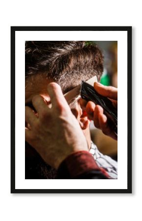 Haircut concept. Man visiting hairstylist in barbershop. Hands of barber with hair clipper, close up. Bearded man in barbershop