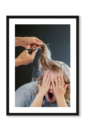 Little boy, toddler is afraid and doesn't want to cut his hair. A baby boy is fearful of getting his haircut for the first time.