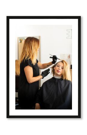 Female hairdresser staining hair of female customer