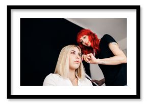 Dyed haired hairstylist adjusting female model's hair at studio