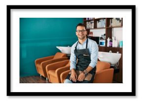 Happy male hairdresser works at hair salon and looks at camera.