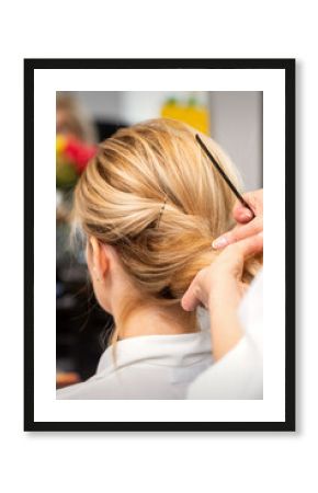 Close-up hairdresser styling blonde hair on the back of the head in a beauty salon