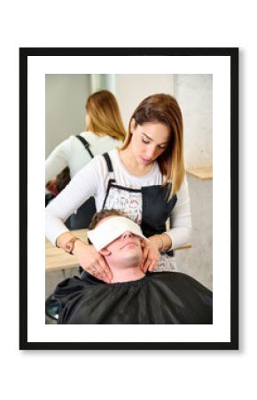 A man in a hairdresser salon and the barber monetizing his face with aftershave