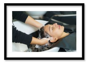 hairdresser is applying shampoo and massaging hair of a customer. Woman having her hair washed in a hairdressing salon..