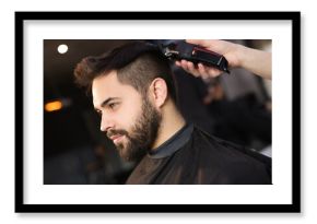 Professional hairdresser working with client in barbershop