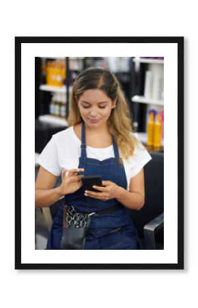Smiling young hairdresser reading feedback from clients in application on smartphone