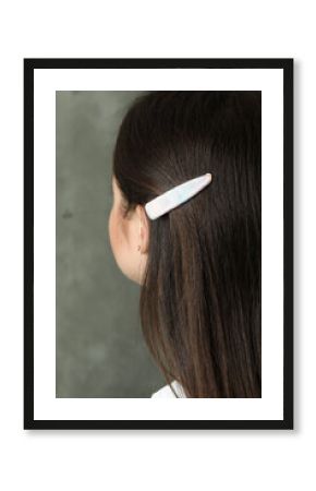 Young woman with beautiful hair clip on grey background, closeup