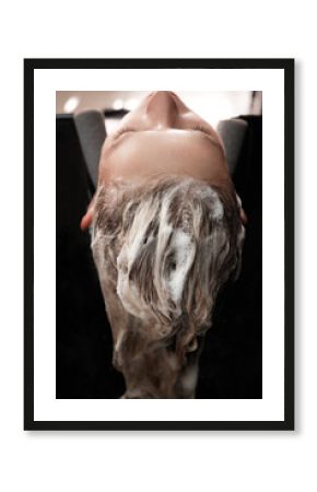 Young woman in a hairdressing salon dyes her hair blond and washing head