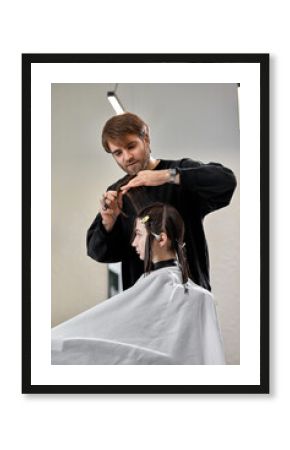 Professional male hairdresser cutting female hair in salon