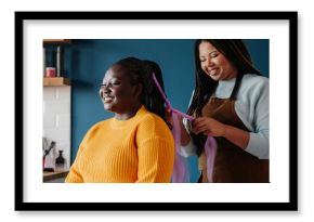 Happy African American hairdresser braiding hair to a female customer in salon