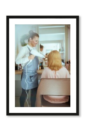 woman hairdresser in beauty salon blowout hair with hair dryer