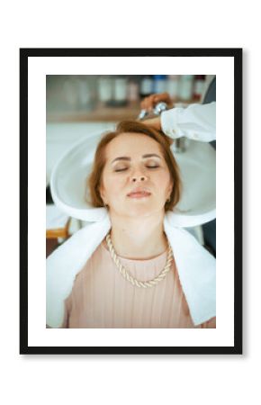 woman hairdresser in modern beauty studio washing hair