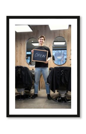 Happy barber posing at camera in hairdressing salon