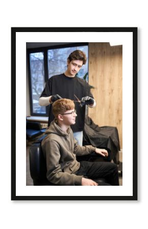 Handsome barber working in contemporary hairdressing salon