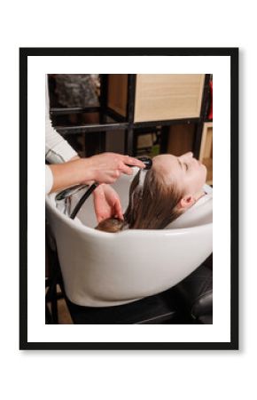 a master in a beauty salon washes a client's hair with shampoo for hair care in a beauty salon