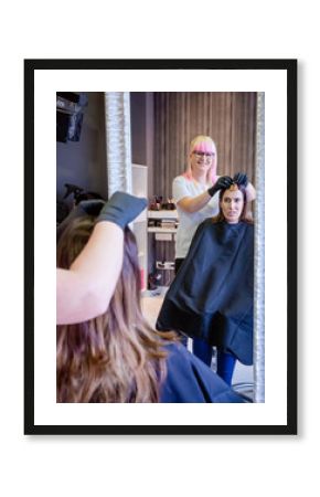 Woman with hairdresser looking hair dye sample in mirror