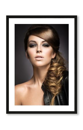 Beautiful girl with bright make-up, perfect skin and hairstyle as a braid.Picture taken in the studio on a gray background