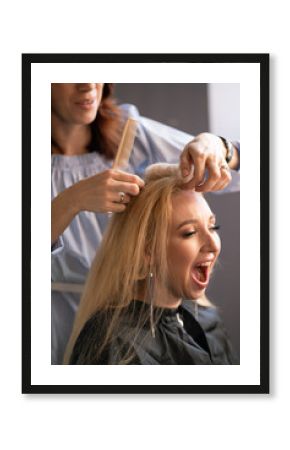 beautiful adult blonde client sits in a chair while a hairdresser master in the salon does her hair with a corrugation and a Perm