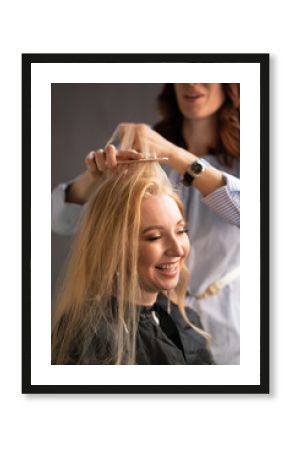 beautiful adult blonde client sits in a chair while a hairdresser master in the salon does her hair with a corrugation and a Perm