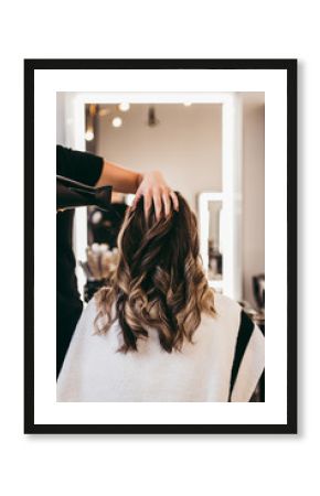 Beautiful brunette woman with long hair at the beauty salon getting a hair blowing. Hair salon styling concept.