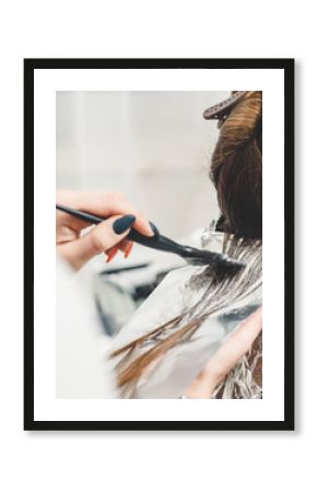 Young professional hairdresser applying dye on clients hair