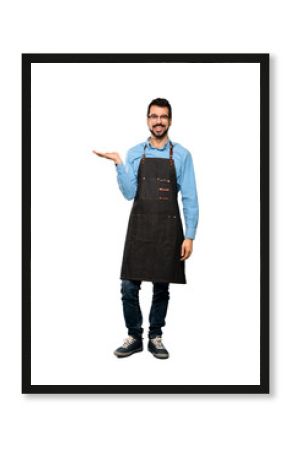 Full-length shot of Man with apron holding copyspace imaginary on the palm to insert an ad over isolated white background
