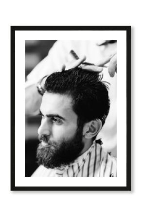 hairdresser or barber does a hairstyle to the client on the background of modern barbershop