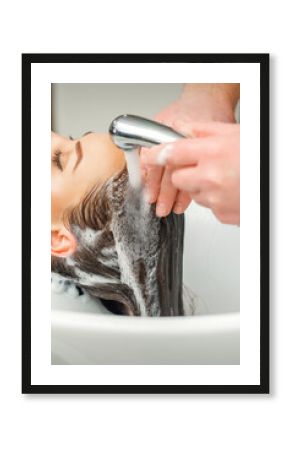 Close up of hands of hairdresser washing hair of woman in sink at beauty salon