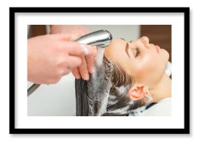 Close up of hands of hairdresser washing hair of woman in sink at beauty salon
