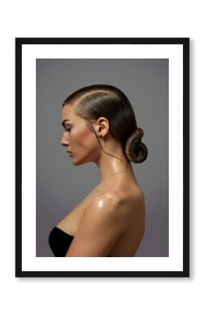 Beautiful young woman with natural make-up and smooth hairstyle gathered in a bunch close-up in profile. Emotions.