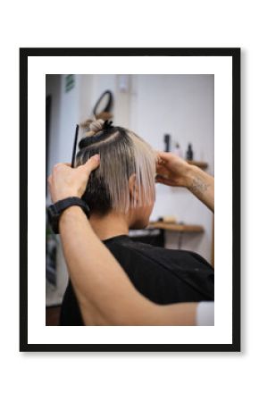 Hairdresser cutting short blonde hair of young female model in salon
